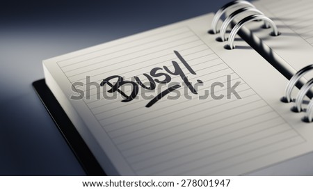 Closeup of a personal agenda setting an important date representing a time schedule. The words Busy written on a white notebook to remind you an important appointment.