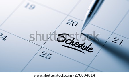 Closeup of a personal agenda setting an important date written with pen. The words Schedule written on a white notebook to remind you an important appointment.
