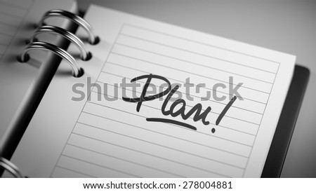 Closeup of a personal agenda setting an important date representing a time schedule. The words Plan written on a white notebook to remind you an important appointment.