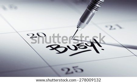 Concept image of a Calendar with a golden dart stick. The words Busy written on a white notebook to remind you an important appointment.