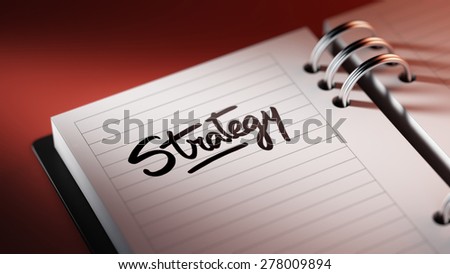 Closeup of a personal agenda setting an important date representing a time schedule. The words Strategy written on a white notebook to remind you an important appointment.