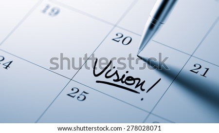 Closeup of a personal agenda setting an important date written with pen. The words Vision written on a white notebook to remind you an important appointment.