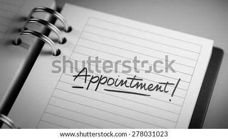 Closeup of a personal agenda setting an important date representing a time schedule. The words Appointment written on a white notebook to remind you an important appointment.