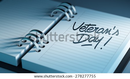Closeup of a personal agenda setting an important date representing a time schedule. The words Veteran\'s Day written on a white notebook to remind you an important appointment.