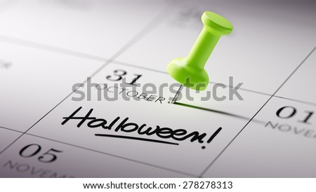 Concept image of a Calendar with a green push pin. Closeup shot of a thumbtack attached. The words Halloween written on a white notebook to remind you an important appointment.