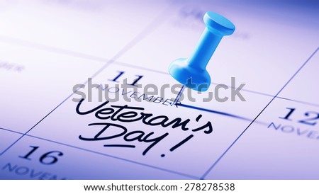 Concept image of a Calendar with a blue push pin. Closeup shot of a thumbtack attached. The words Veteran\'s Day written on a white notebook to remind you an important appointment.