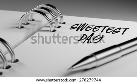 Closeup of a personal agenda setting an important date writing with pen. The words Sweetest Day written on a white notebook to remind you an important appointment.