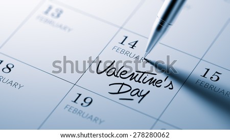 Closeup of a personal agenda setting an important date written with pen. The words Valentine's Day written on a white notebook to remind you an important appointment.