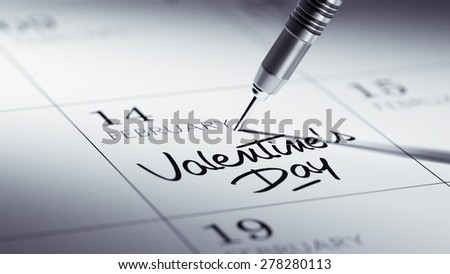 Concept image of a Calendar with a golden dart stick. The words Valentine\'s Day written on a white notebook to remind you an important appointment.