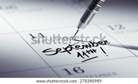 Concept image of a Calendar with a golden dart stick. The words September 11th written on a white notebook to remind you an important appointment.