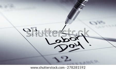 Concept image of a Calendar with a golden dart stick. The words Labor Day written on a white notebook to remind you an important appointment.