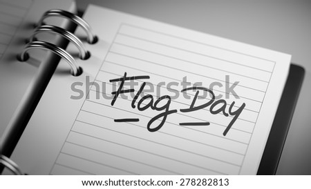 Closeup of a personal agenda setting an important date representing a time schedule. The words Flag Day written on a white notebook to remind you an important appointment.