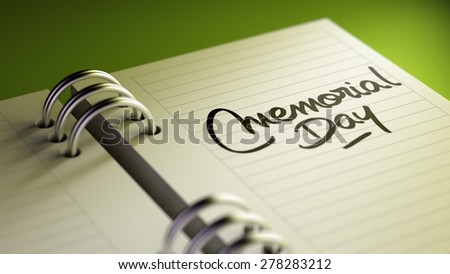 Closeup of a personal agenda setting an important date representing a time schedule. The words Memorial Day written on a white notebook to remind you an important appointment.