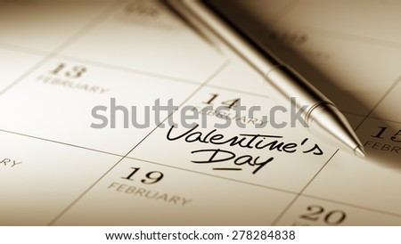 Closeup of a personal agenda setting an important date written with pen. The words Valentine\'s Day written on a white notebook to remind you an important appointment.