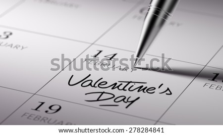 Closeup of a personal agenda setting an important date written with pen. The words Valentine\'s Day written on a white notebook to remind you an important appointment.