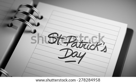 Closeup of a personal agenda setting an important date representing a time schedule. The words St. Patrick\'s Day written on a white notebook to remind you an important appointment.