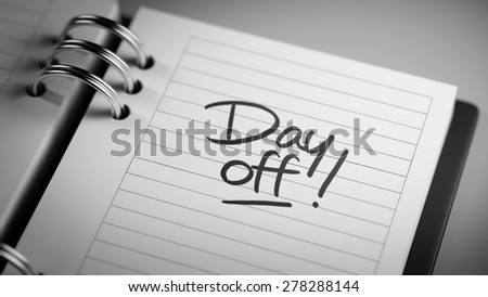 Closeup of a personal agenda setting an important date representing a time schedule. The words Day off written on a white notebook to remind you an important appointment.