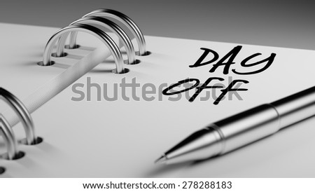 Closeup of a personal agenda setting an important date writing with pen. The words Day off written on a white notebook to remind you an important appointment.