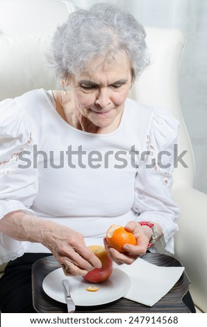 old woman peels tangerine