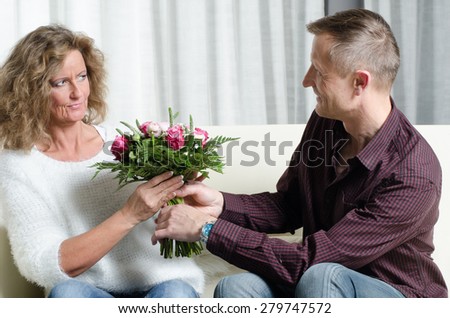 man is giving a bouquet of flowers to woman - she is in doubt