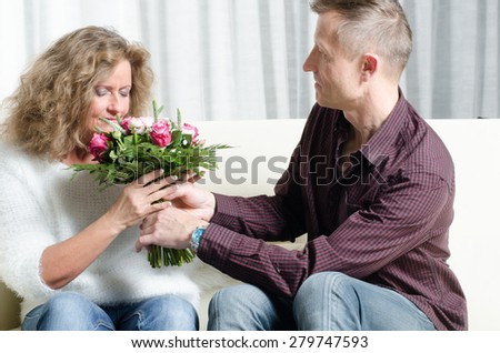 Man is giving a bouquet of flowers to woman - she is smelling th