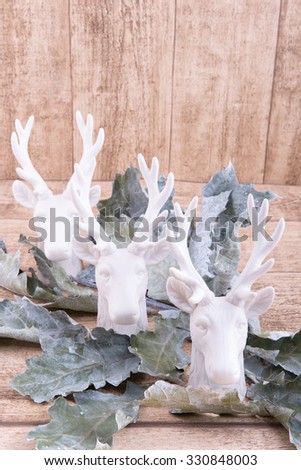 three deer heads and leafs on wooden background with space for own text