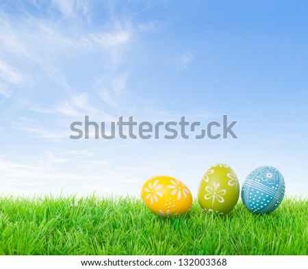 Colorful easter eggs on meadow over bright spring sky.