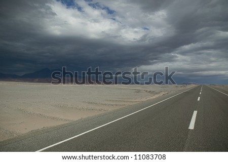 Highway through a desert with a thunderstorm.