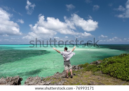 Man raises his hands in worship on front of the amazing green blue pacific ocean at Miyakojima, Okinawa, Japan.