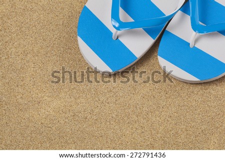 Blue flip flop shoes and on a yellow sand beach