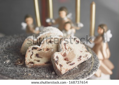 traditional stollen christmas cake on a plate and angel candle holders on a background