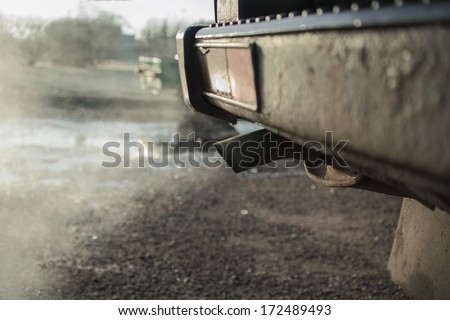 old car tail pipe with exhaust coming out, outdoor blurred shot,particular  focused on the subject