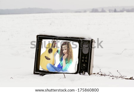 abandoned broken retro tv in a snow field with no power supply, a young girl with  guitar on the screen, concept of technologies