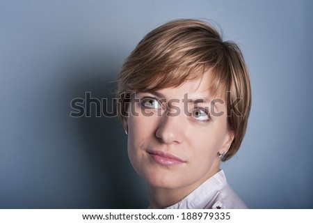 Nice portrait of a romantic woman. The woman posing in an artistic manner, appealing as a typical dreamer, studio shot on blue