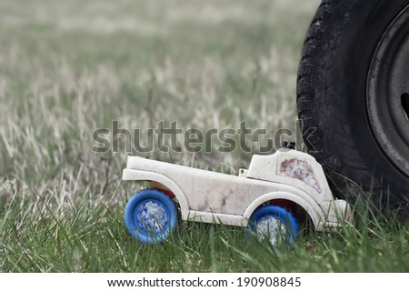 Close up of a smashed toy car, concept of a danger on the roads. Outdoor horizontal shot with particular focus and blurred background