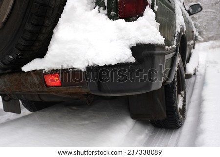 Rear of an old off road vehicle with a red brake light on, outdoor shot in snowy weather