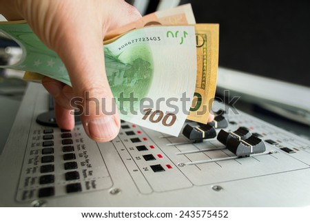 Close up of DJ hand holding money and playing on mixing deck, concept of entertainment industry