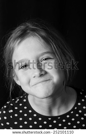 Studio shot of a beautiful teenage girl with tilted head, making face, in black and white