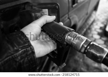 Close up of a driver hand refueling car,everyday scene in black and white