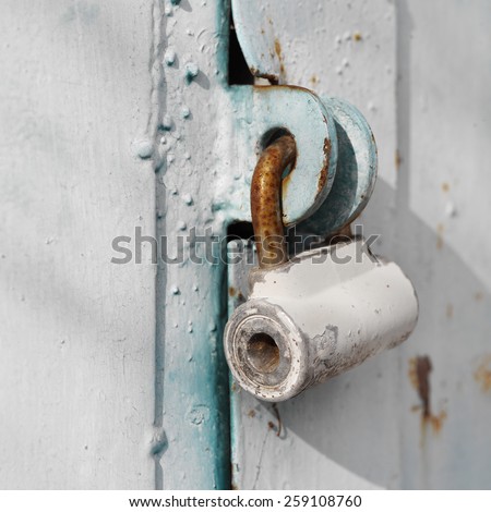 Rusty padlock on a metal entrance door, concept of security. Outdoor shot with selective focus