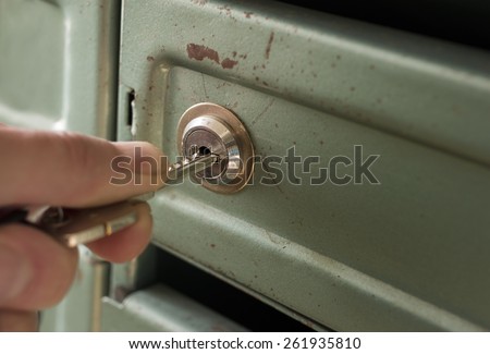 Male hand opening a metal box, safe or post box, concept of safety and security. Indoor shot with selective focus