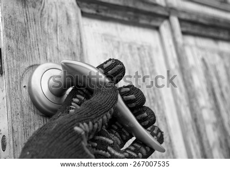 Closeup of a burglar hand wearing knitted glove on a door handle, concept of safety