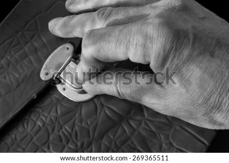 Male hand on a leather briefcase lock, concept of secrecy in black and white