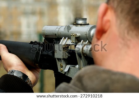 Looking down the barrel of a russian sniper rifle being held by a non identifiable man dressed in casual wear