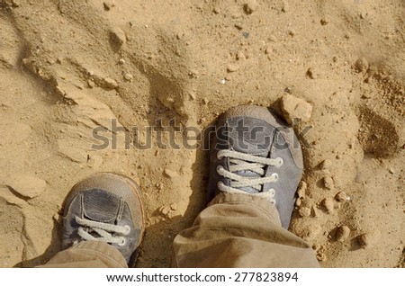 Overhead shot of the human legs wearing shoes stuck in the sand, concept of climate change