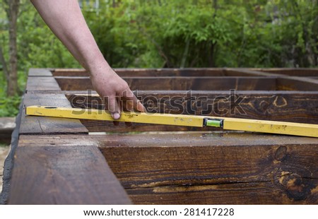 Spirit-level ruler is hand held by male hand over a wooden frame