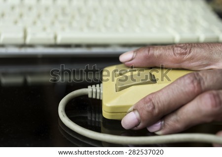 Female hand using retro computer mouse, keyboard in the blurred background