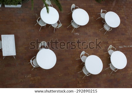 Abandoned plastic tables and chairs at the summer veranda, concept of back end of tourism, overhead shot