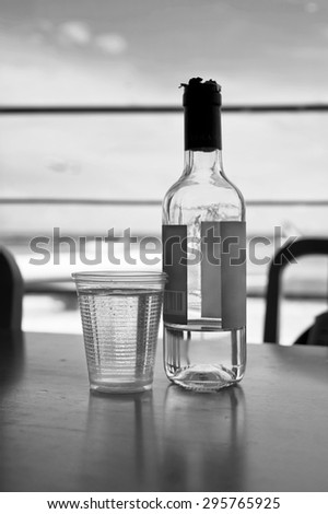 Bottle Of Wine and plastic glass on a table, airport with planes in the blurred background