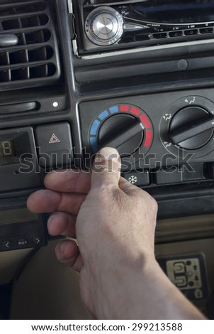 Male hand on a car climate control, angled vertical shot